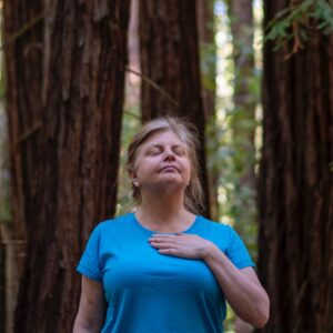 person forest bathing in the redwoods with hand to heart