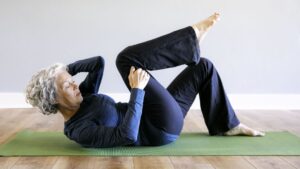 A woman laying on a green yoga mat