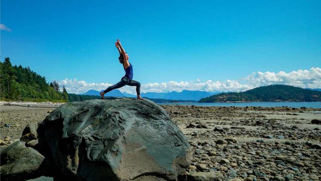 Fiji McAlpine yoga pose on large rock on beach