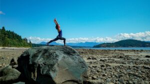 Fiji McAlpine yoga pose on large rock on beach