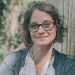 Head shot of Christina Conrad, white woman with brown hair and glasses, smiling