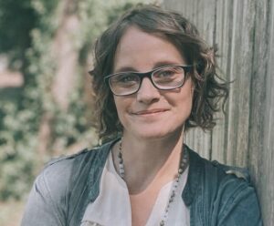 Head shot of Christina Conrad, white woman with brown hair and glasses, smiling