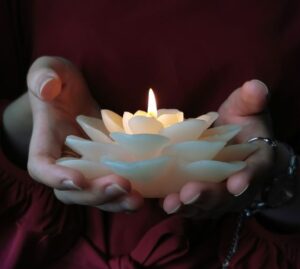 hands holding a lotus flower candle