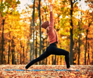 Person practicing yoga outdoors among colorful autumn trees during a peaceful fall retreat at Song of the Morning