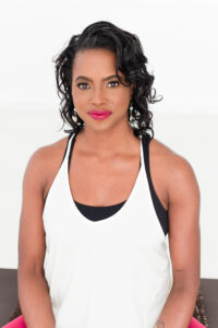 A Black woman with medium-length dark hair in a white top in front of a white background.