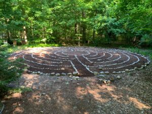 A stone labyrinth on the ground surrounded by forest.