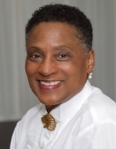 A headshot of a smiling Black woman with short dark hair in a white shirt.