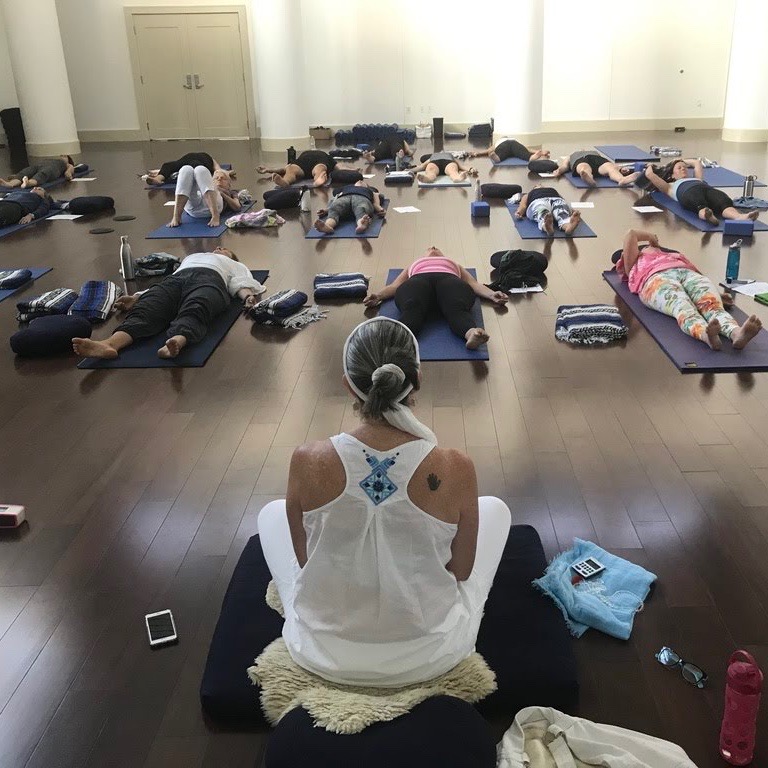 a woman in white leads a yoga class