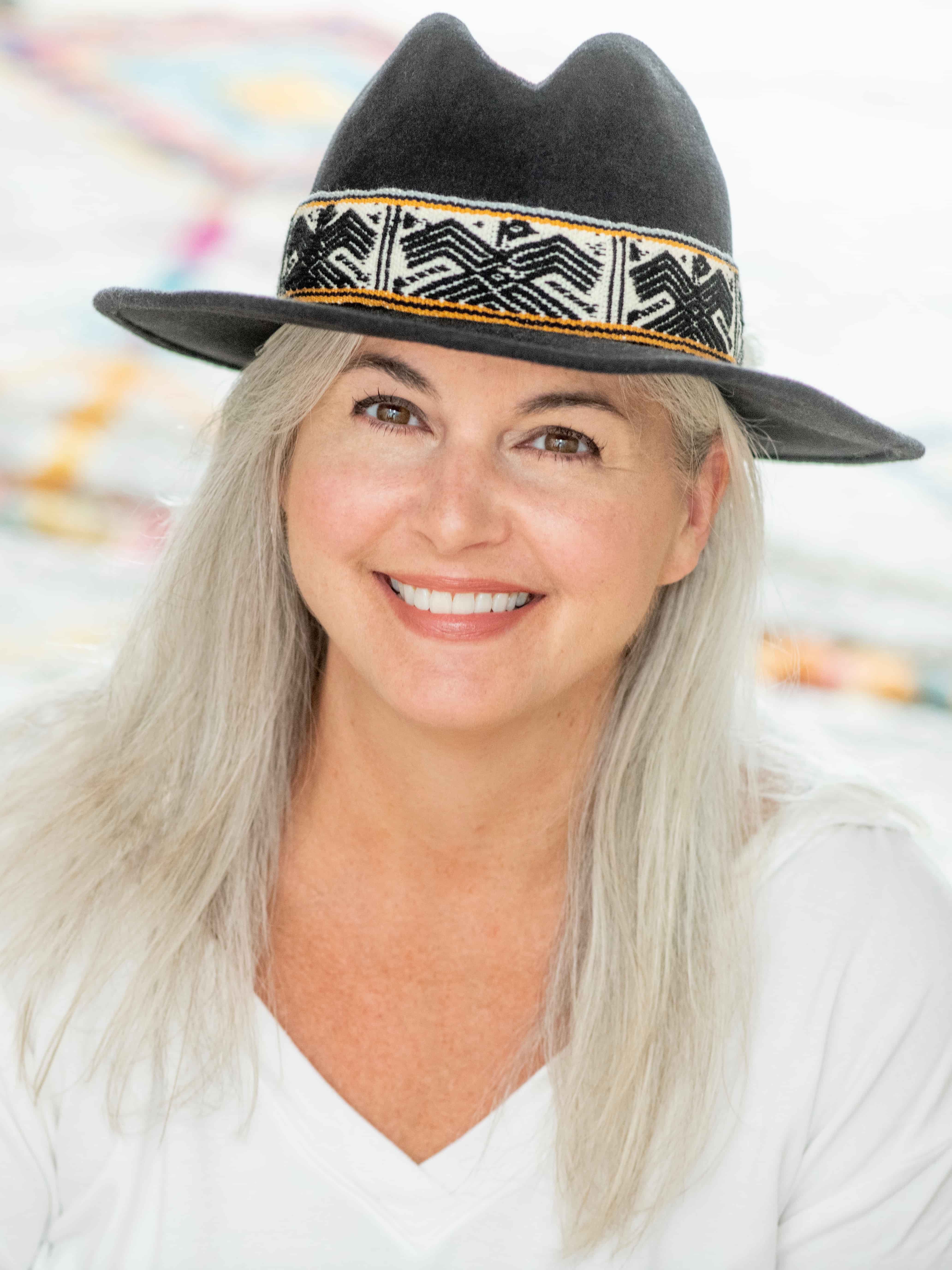 smiling woman with long grey hair and black cowboy hat