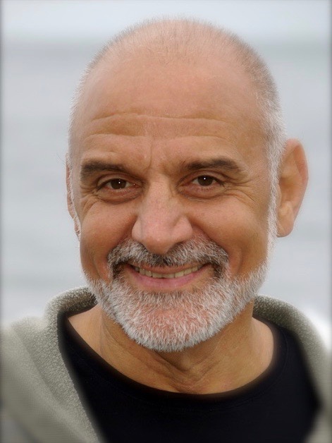 Clost-cropped image of bald man with grey beard, smiling