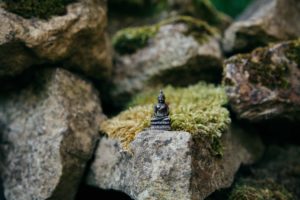 small statue of milarepa on a mossy rock