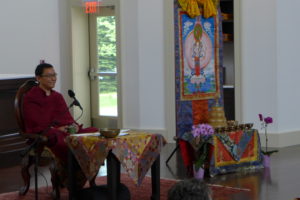 A Buddhist Rinpoche in a chair with Tibetan Buddhist trappings