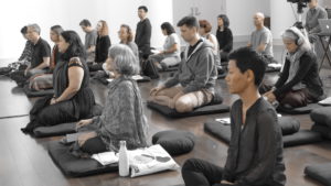 a group of peopel sitting on meditation cushions