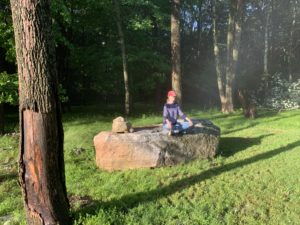 a woman meditates outdoors on a rock 