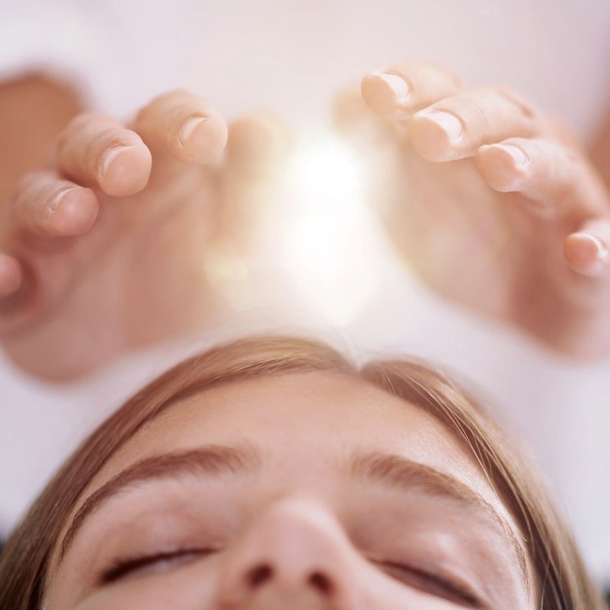 hands performing reiki over a woman's head