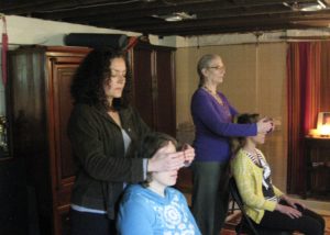 two students stand behind feloow students learning and practicing reiki