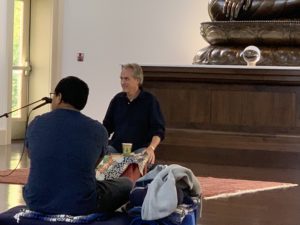 two men sit in a meditation hall
