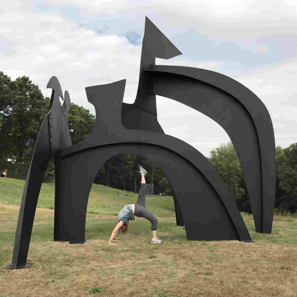 woman doing yoga under a sculpture
