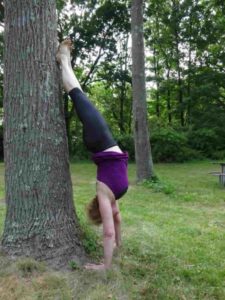 Amy Hamilton does a handstand against a tree