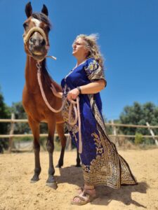 woman in late forties, early fifties standing beside a brown horse in a powerful connection between the two