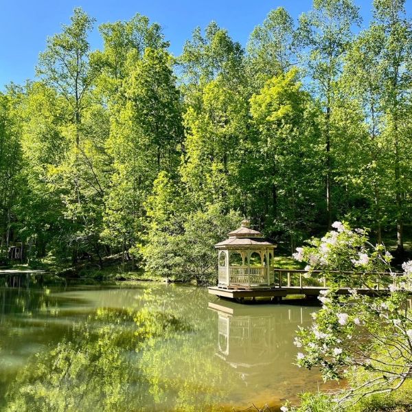 Beautiful gazebo on the Sanctuary pond with lush surroundings of trees and flowers