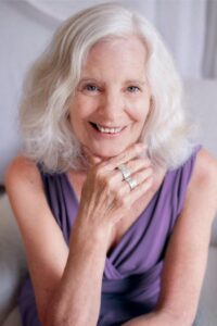 A headshot of Susan Tate in a purple top and smiling, 